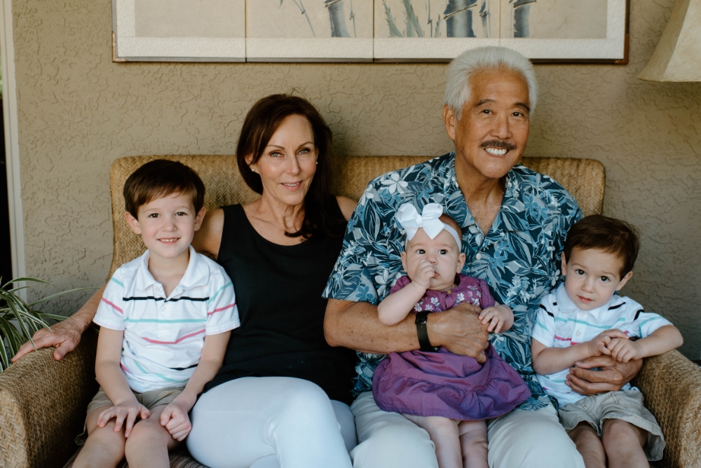 Dr Yamahata and his family sitting on a chair smiling. The doctor is holding his 2 young children one in each arm.